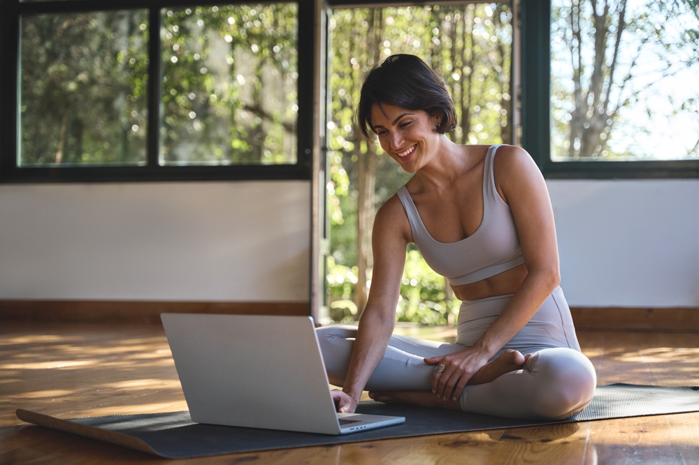 Jeune femme, coach et formatrice de yoga, heureuse, assise sur un tapis dans un studio