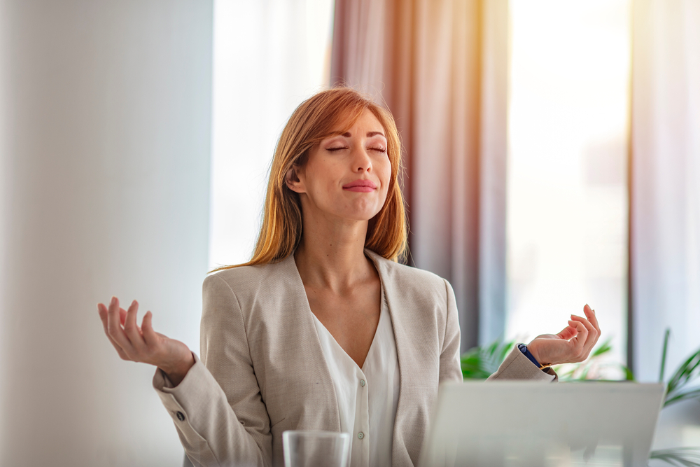 Femme d'affaires souriante se reposant et pratiquant la méditation yoga