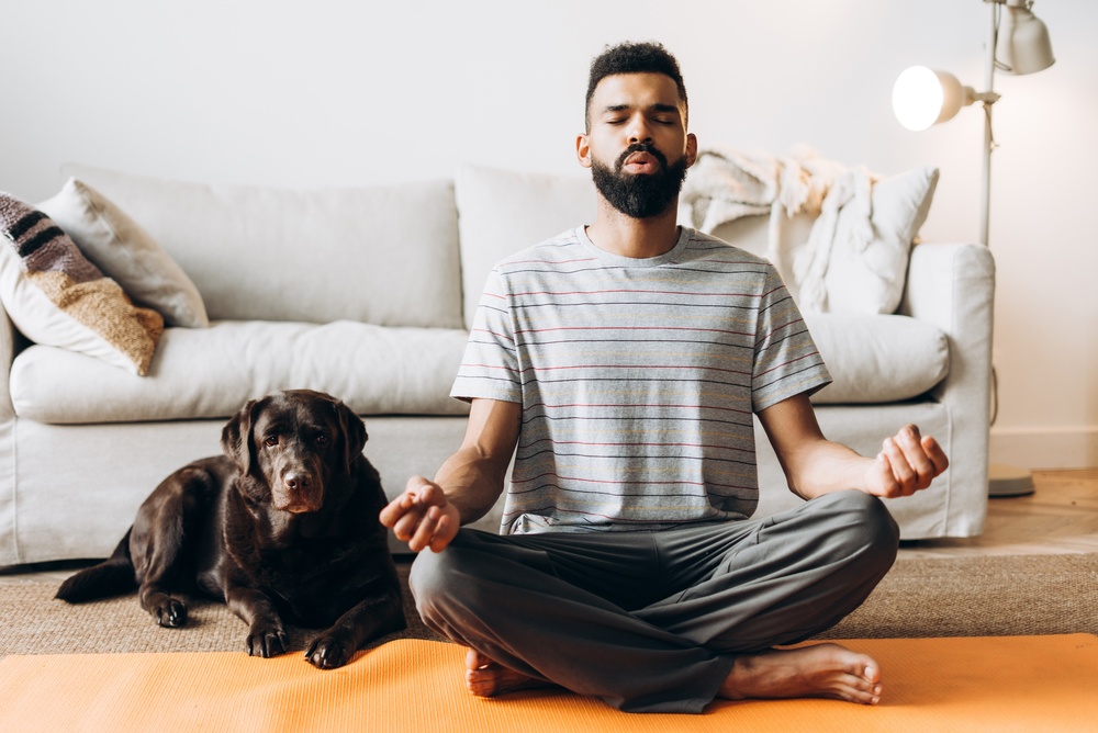 Jeune homme pratiquant la méditation de pleine conscience sur un tapis de yoga en intérieur