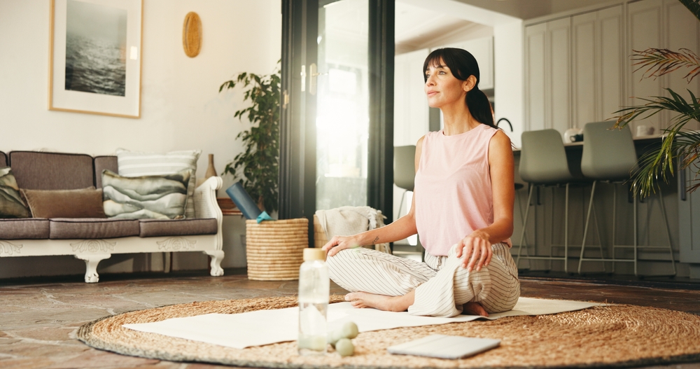 Femme réfléchissant pendant une séance de méditation et de yoga à la maison, dans une ambiance zen