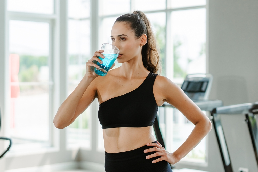Femme buvant une boisson de couleur bleue dans un verre