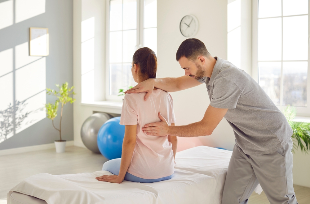 Ostéopathe et physiothérapeute examinant une jeune femme dans un bureau moderne