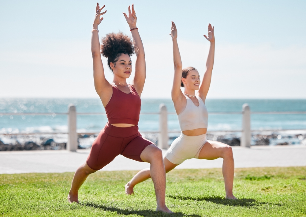 Amies pratiquant le yoga et le fitness ensemble en extérieur sur la plage, en pleine nature