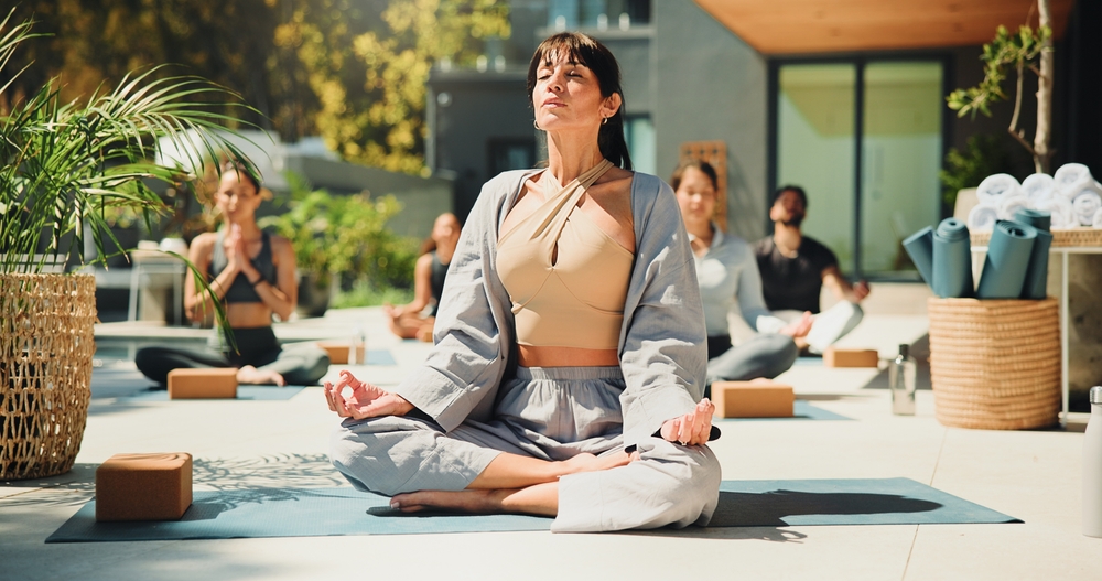 Instructeur et participants pratiquant le yoga en extérieur en position du lotus pour la méditation